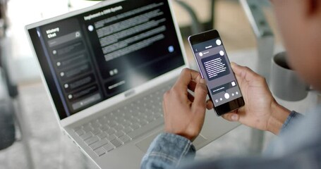 African american businessman using smartphone and laptop with ai chatbot at home, slow motion - Powered by Adobe