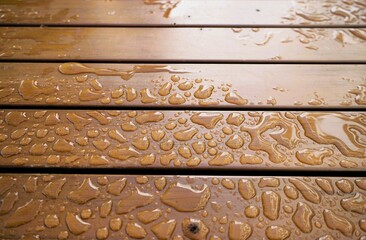 Nasse braune Lattenholztischfläche mit Regentropfenmuster am Morgen im Herbst