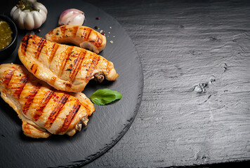 Grilled chicken breast with vegetables on the black stone tray.