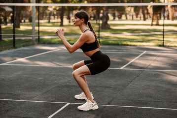 Obraz premium A young girl with an athletic figure is doing fitness at the sports ground. fitness trainer. Slim body