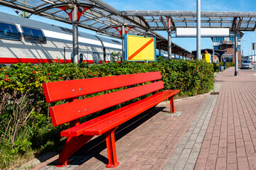 Obraz premium Emden Aussenhafen train station with red bench outside, Germany