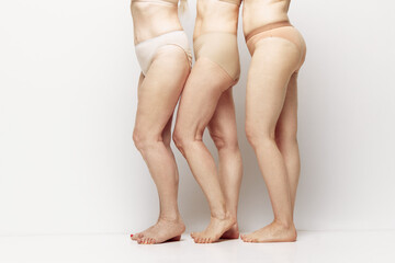 Cropped side view image of female legs in underwear against grey studio background. Natural body of senior women. Concept of age, natural beauty. body and skin care, healthy lifestyle