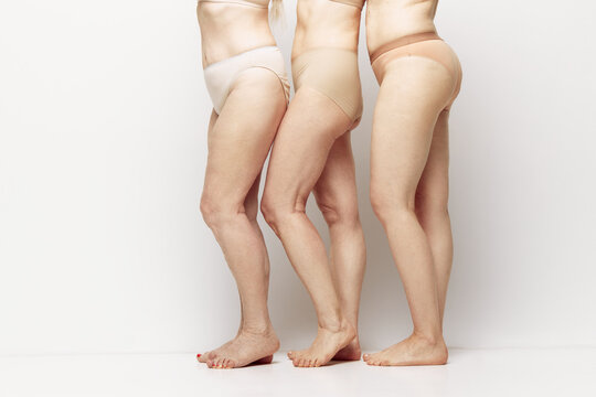 Cropped side view image of female legs in underwear against grey studio background. Natural body of senior women. Concept of age, natural beauty. body and skin care, healthy lifestyle