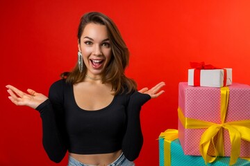 young charming brunette received a lot of gifts for the new year on a red background