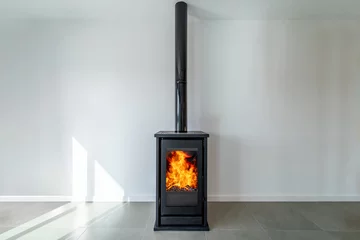 Foto op Plexiglas Fireplace inside house modern living room. Cosy living room with wood burner stove with burning flame behind a glass door © Joao