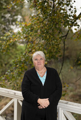 Elder woman standing on a wooden bridge