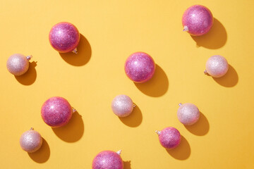 A lot of blinking baubles in pink color are arranged over the yellow background. Christmas is often...