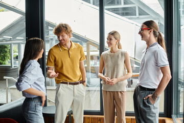 four coworkers in business casual clothing happily chatting to each other, coworking concept