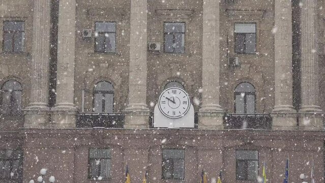 Mykolaiv, Ukraine - 02202021: View of large wall clock on old municipal council building against backdrop of poor visibility and fog from falling snow during Christmas
