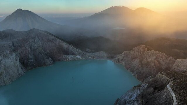 flying towards Ijen volcanic caldera, Ijen volcano crater in East Jawa, Indonesia, aerial view of volcanic lake with sulphur gases at dawn, tourism in Ijen volcano national park in Jawa