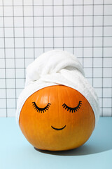 Skin and face care concept - pumpkin with eyelashes and towel