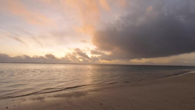 Horizontal pane view lookout to Ocean Sea horizon in the Pacific during sunset orange pink sky with cloud in calm and relaxation turquoise lagoon with soft wave ponding on the beach in Aroa Rarotonga