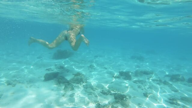 Sexy young female Caucasian girl woman dress in black bikini swimming in shallow calm lagoon of turquoise blue water with white sandy seabed during daytime in Aroa Rarotonga Cook Islands Pacific