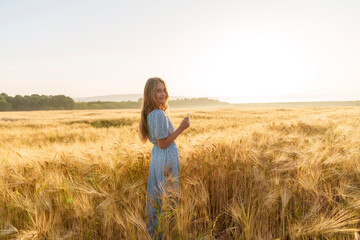 Smiling girl with long hair standing amidst wheat crop in field