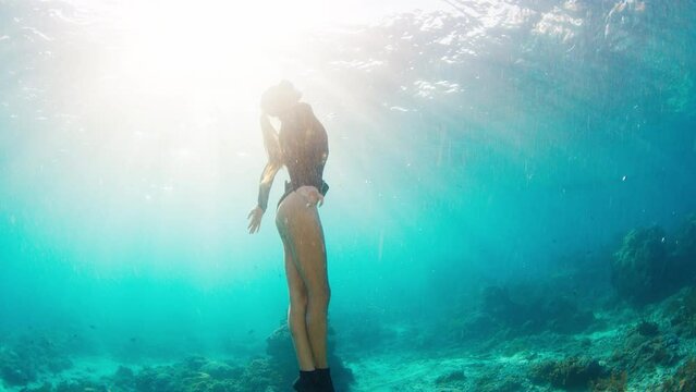 Young woman swims in the ocean. Female freediver glides underwater