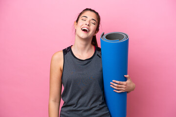 Young Brazilian sport woman going to yoga classes while holding a mat isolated on pink background...