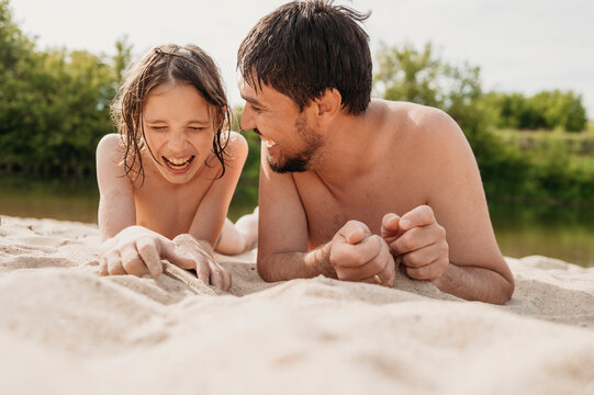 Cheerful father and son lying on sand and enjoying at beach