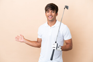 Young golfer player man isolated on ocher background extending hands to the side for inviting to...