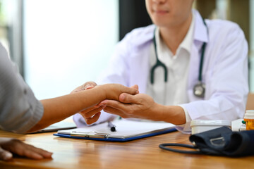 Caring male physician holding elderly female patient hands to comforting, expressing healthcare sympathy. Healthcare concept