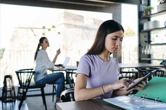 Portrait of pretty brunette using digital tablet at table in coworking office