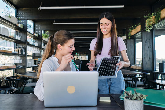 Two young women working together on sustainable resources project at coworking space
