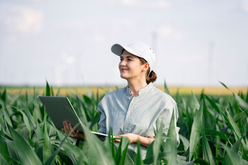Smiling businesswoman holding laptop standing amidst plants