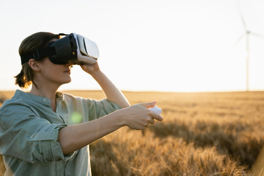 Agronomist using virtual reality headset standing in wheat field