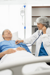 Obraz premium Doctor uses a stethoscope listen to the heart rate for the patient to lie in the patient’s bed. Medical concept. Health check.