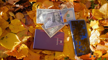 Naklejka na ściany i meble The budget travel concept with dollars and smart phone in Autumn fall background 