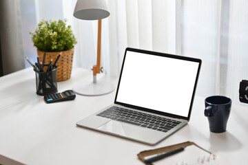Laptop computer, calculator, coffee cup, pencil holder and houseplant on white working desk