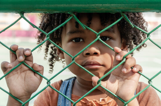 Boy with curly hair near fence