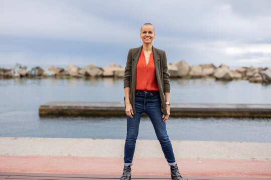 Smiling shaved head woman standing at pier