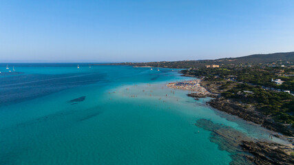 Fototapeta na wymiar Aerial view of La Pelosa beach at sunny summer day. Stintino, Sardinia island, Italy. Drone view of sandy beach, playing people, clear blue sea.