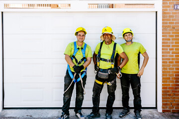 Happy engineers wearing hardhats standing in front of garage door