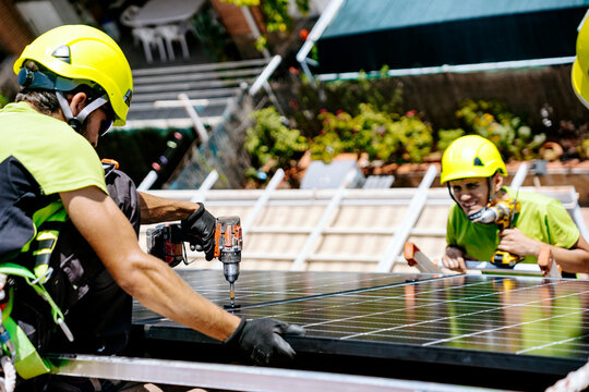 Engineers with drill machine installing solar panels on roof