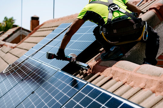 Engineer with hand tool installing solar panel on sunny day