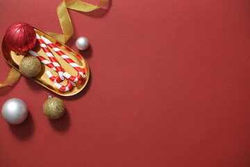 Christmas composition with baubles, candy canes and yellow ribbon decorated on red background. Blank space for add text or best wishes. Xmas card design ideas