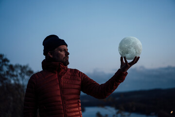 Mature man holding and looking at moon model under sky