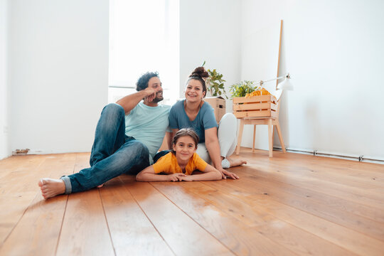 Smiling man and woman with daughter lying on floor at home