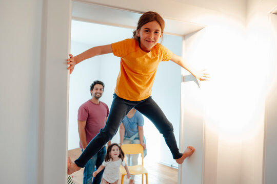 Girl Climbing On Wall With Family In Background