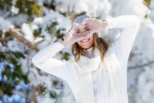Smiling woman making heart sign in winter landscape