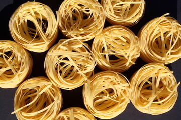 Round spaghetti lies on a black background.	