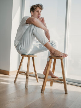 Contemplative man sitting on wooden stools at home