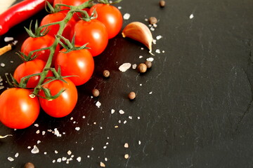  Red cherry tomatoes sprinkled with coarse salt lie on a black background.
