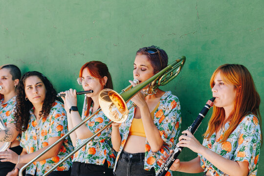 Women practicing musical instruments near wall