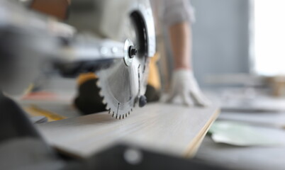 Master cutting piece of laminated wood shelves with manual electric saw in apartment. Laminate cutting machine concept