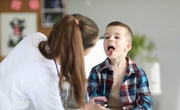 Doctor consults little boy with sore throat. Inflammation of tonsils of adenoids and tonsillitis in children