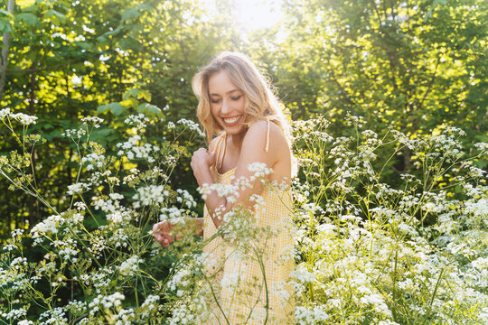 Cheerful woman standing amidst flowers in forest