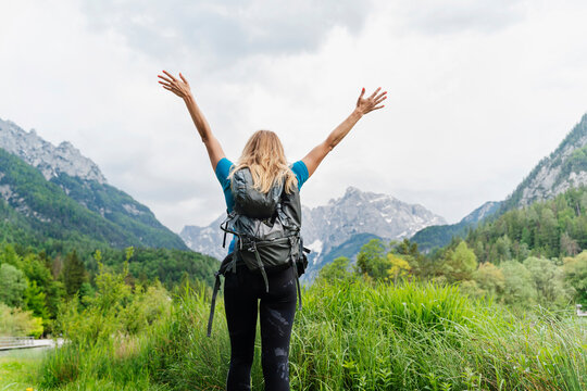 Hiker with arms raised enjoying mountain view in nature