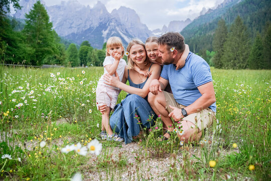 Daughters embracing father and mother crouching in meadow